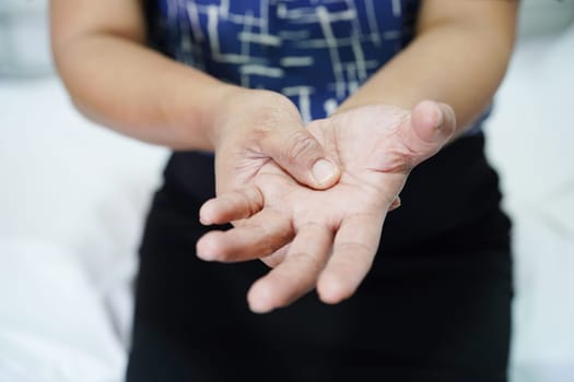 Asian senior woman pain her hand and finger, De Quervain's tenosynovitis.