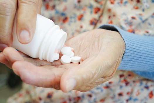 Asian elderly woman holding pill drug in hand, strong healthy medical concept. 