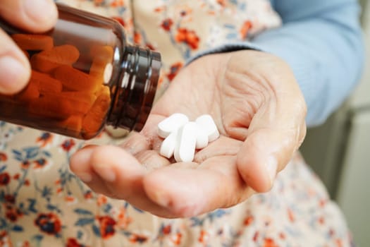 Asian elderly woman holding pill drug in hand, strong healthy medical concept. 