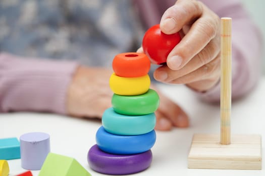 Asian elderly woman playing puzzles game to practice brain training for dementia prevention, Alzheimer disease.