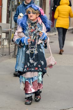 LYON, FRANCE - DECEMBER 11, 2016: Strange woman in a colored dress with makeup and a cigarette