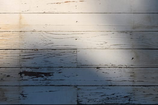 Soft sunlight illuminates aged wooden planks, creating a serene atmosphere with intricate shadows and textures.