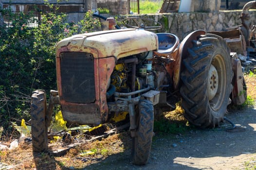 Rusting tractor sitting idle beside a path surrounded by wild plants, evoking nostalgia for rural life.