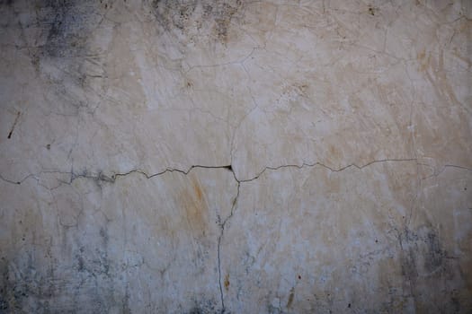 A weathered wall with noticeable cracks displays its age and history in a charming, rustic environment.