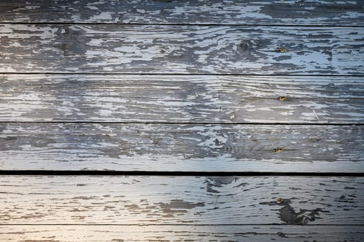 Sunlight casts a gentle glow on old wooden planks, showcasing their texture and history in an outdoor space.