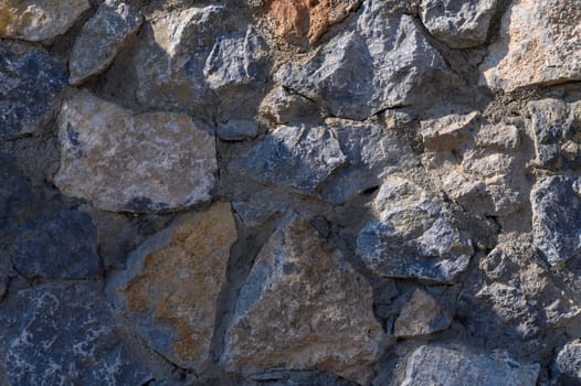 Sunlight reveals the rich textures and colors of a weathered stone wall, showcasing nature's architectural artistry.