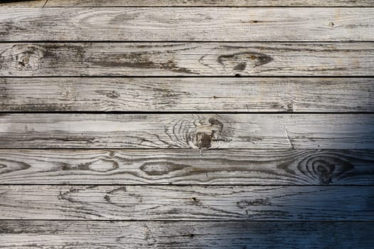 Sunlight casts gentle shadows on rustic wooden planks, revealing intricate textures and patterns in a serene setting.