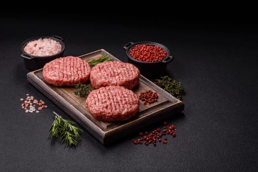 Fresh raw ground beef burger patty with salt and spices on textured concrete background