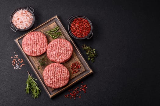 Fresh raw ground beef burger patty with salt and spices on textured concrete background