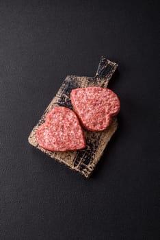Raw beef or pork burger patty in the shape of a heart with salt, spices and herbs