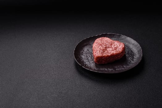 Raw beef or pork burger patty in the shape of a heart with salt, spices and herbs