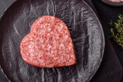 Raw beef or pork burger patty in the shape of a heart with salt, spices and herbs