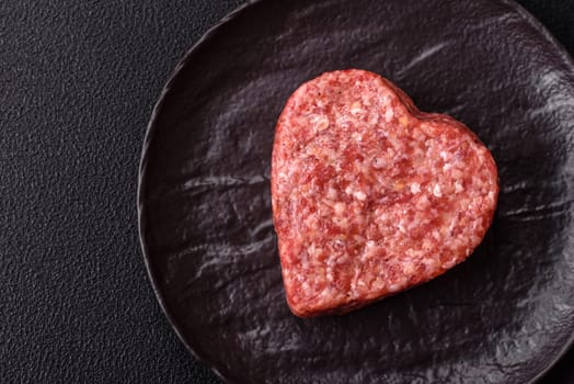 Raw beef or pork burger patty in the shape of a heart with salt, spices and herbs
