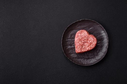 Raw beef or pork burger patty in the shape of a heart with salt, spices and herbs