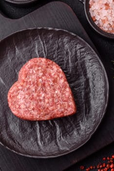 Raw beef or pork burger patty in the shape of a heart with salt, spices and herbs