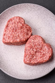 Raw beef or pork burger patty in the shape of a heart with salt, spices and herbs