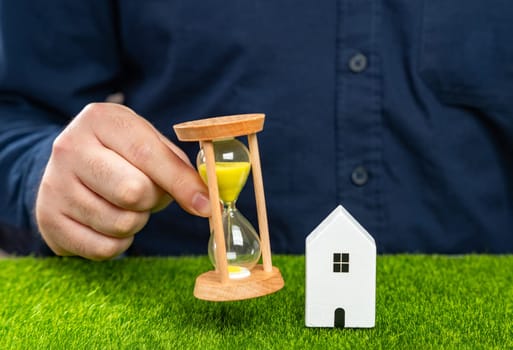A man holds an hourglass near his house. Rent and realty. Mortgage and loan payments. Limited supply. Long-term lease terms. Legislation on evicting tenants or squatters.