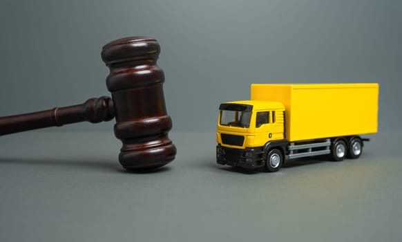 Yellow truck and judge's gavel. Court case. New laws and acts. Restrictions and regulations. Bankruptcy. Sale of assets of a transport company through auction.