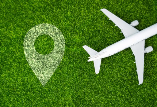 Airplane and geolocation sign on the grass. Travel and business trips. Transport system and infrastructure. Air communication. World flight routes.