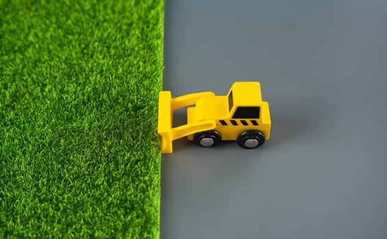 The bulldozer removes the grass and leaves the concrete. The concept of destruction of nature for technogenic development. Expanding cities space . Urbanization, increasing influence on environment.