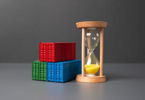 Shipping containers and hourglass. Freight and shipping costs. Delivery duration. Logistics and transportation of commercial cargo. Container rental.