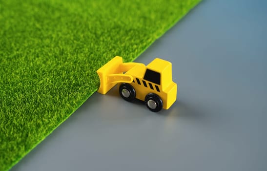 A bulldozer expands the construction area, removing greenery in favor of gray concrete. Destruction of nature for technogenic development. Urbanization, increasing influence on environment.