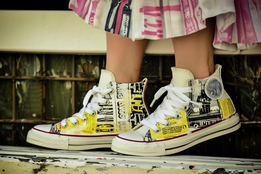 Young adult sitting on a park bench, showcasing custom sneakers with unique, detailed designs.
