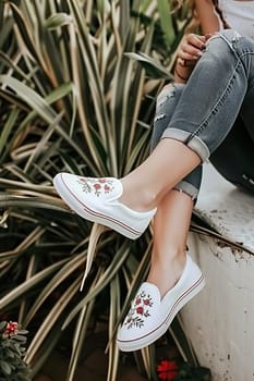 Young adult sitting on a park bench, showcasing custom sneakers with unique, detailed designs.