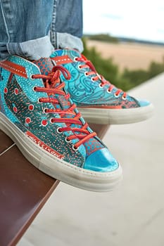 Casual fashion scene of a young person sitting, highlighting artistic sneakers with textured patterns.