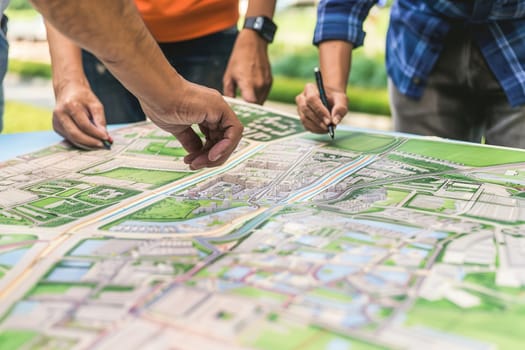 Planners collaborating on eco-city project, reviewing detailed plans on a large table covered with sketches.