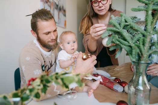 A joyful family decorates Christmas ornaments with their baby, creating cherished holiday memories together