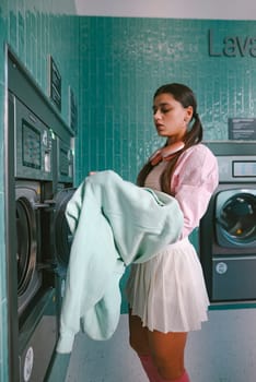 A fashionable woman is gracefully folding her laundry in a lively, colorful, and vibrant laundromat setting