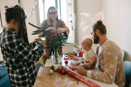 A delightful family is joyfully decorating a vibrant festive Christmas tree while wrapping beautiful gifts together