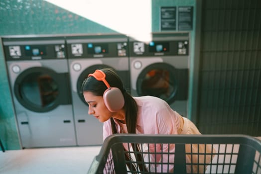 A woman finds joy in listening to her favorite music while she does her laundry in a trendy modern laundromat