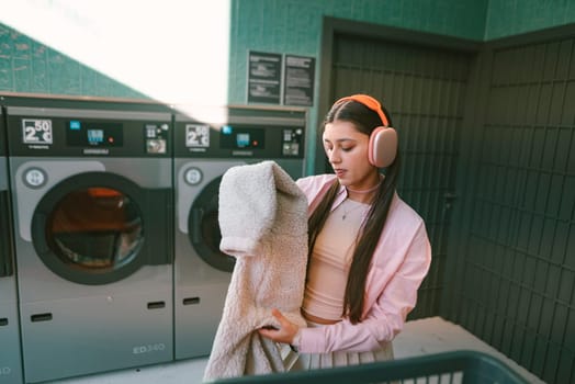 A young woman is happily enjoying her laundry day at a stylish laundromat, wearing cozy attire and headphones