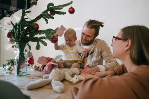 A heartwarming and joyful family moment featuring a baby surrounded by colorful holiday decorations and festive cheer