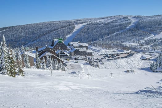View of a winter snowy mountain ski resort with groomed slopes. Horizontally. 