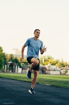 A man exercises high knees on a track, showcasing his speed and agility. The sun rises in the background, illuminating the training facility and surrounding greenery.