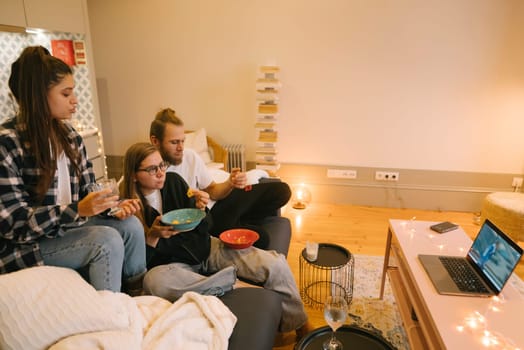 Three close friends gathered in a warm and cozy living room, happily enjoying a movie night filled with snacks