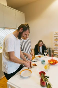 A group of friends happily enjoying the art of cooking and sharing a delicious meal in a cozy kitchen