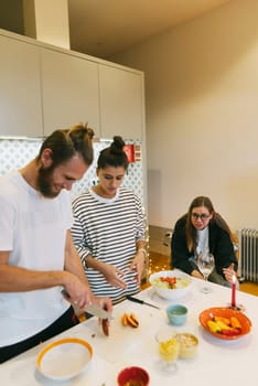A casual and enjoyable gathering of friends preparing delicious food together in a stylish and modern kitchen