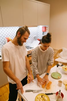 A couple happily enjoying each others company while cooking together, preparing healthy meals in a stylish kitchen