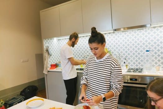 A cozy kitchen scene featuring people preparing food together, highlighting teamwork and culinary creativity.