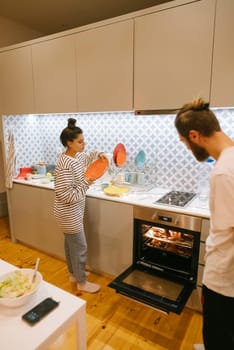 A couple joyfully preparing food together in a stylish, modern kitchen, highlighting their teamwork and culinary skills