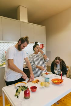 Friends joyfully preparing a delicious meal in a stylish kitchen, showcasing teamwork and creativity in cooking