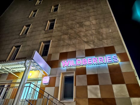 Kirov, Russia - November 12, 2024: Vibrant logo of an online marketplace illuminates a modern building's exterior at night, attracting attention with its colors.