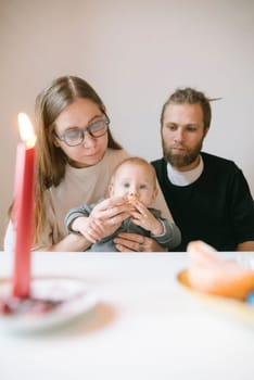A loving family shares a warm moment with their baby, enjoying a cozy candlelit dinner and creating memories