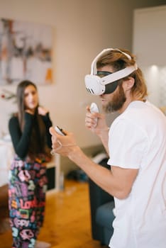 One person is immersed in virtual reality while another keenly observes the essence of modern gaming