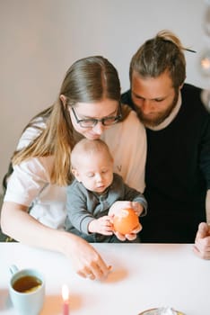 A tender family moment where parents joyfully engage with their adorable baby at home during playtime