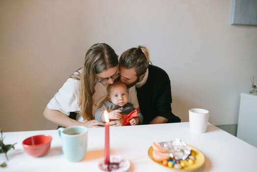 A loving family enjoys and shares a tender, heartwarming moment with their adorable baby at a cozy dining table